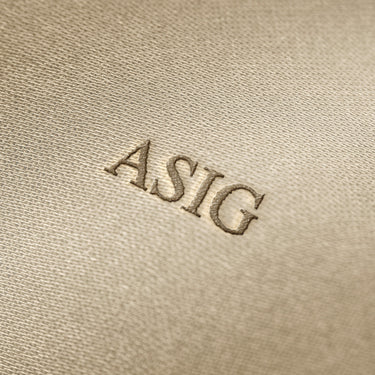 Soft beige fabric close-up showing a smooth, heavyweight knit texture with gentle folds and subtle draping.