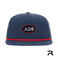A navy blue performance snapback hat featuring a red rope detail and a central navy oval patch with a red embroidered border.